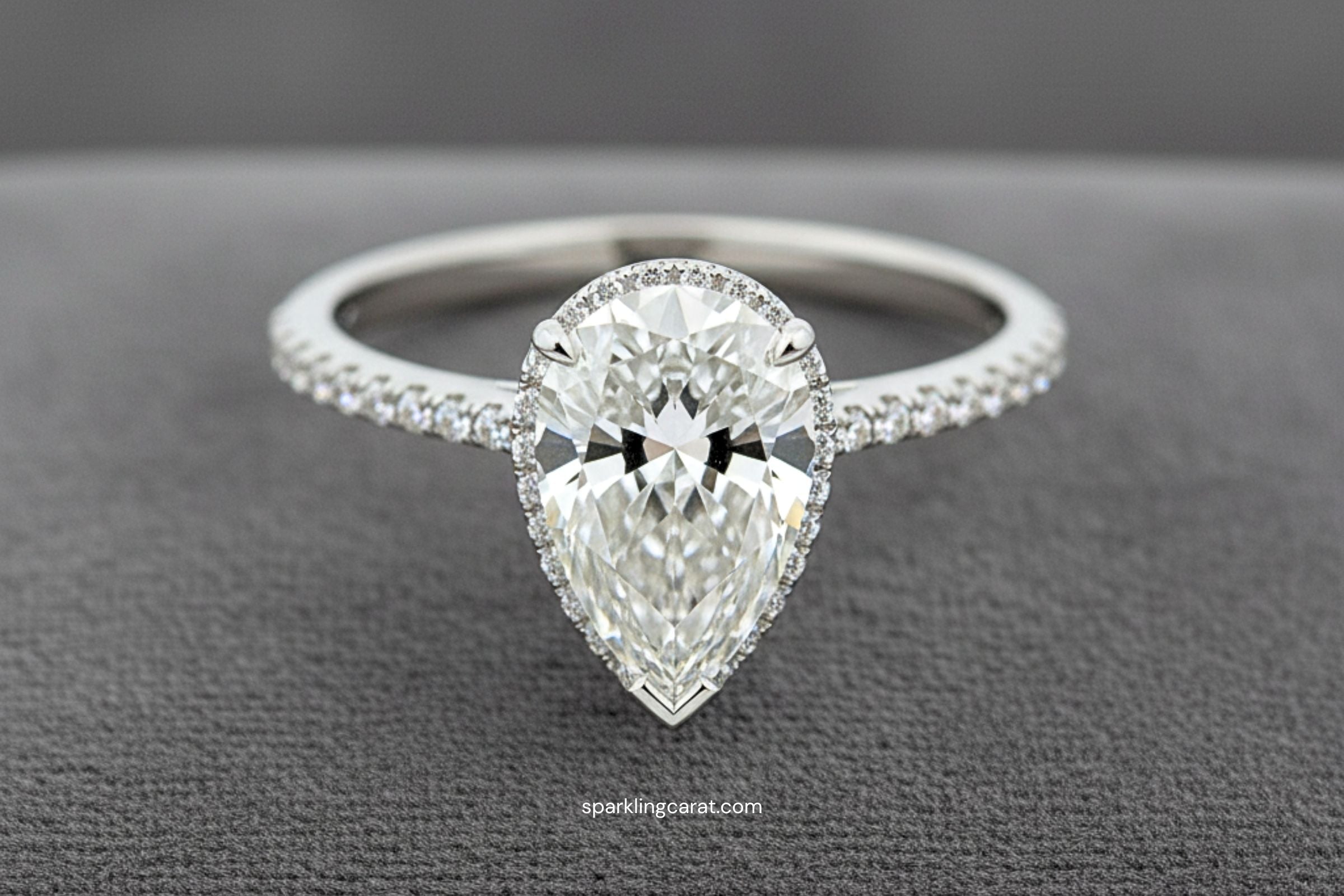 Pear-shaped diamond engagement ring with hidden halo in recycled gold setting, showcasing flattering elongated silhouette.