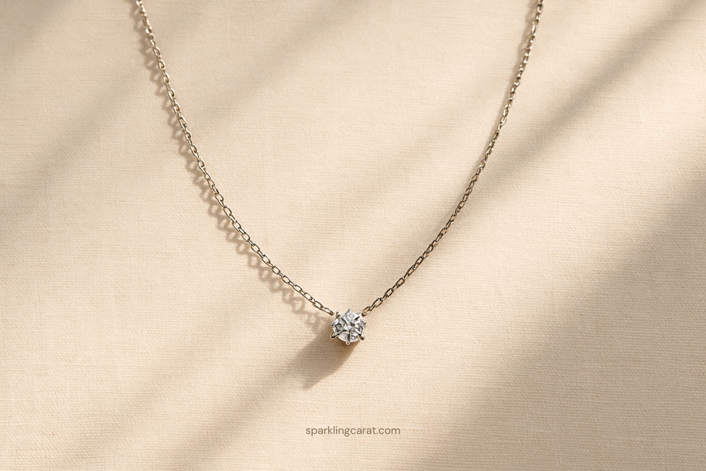 Minimalist floating diamond necklace displayed on soft neutral fabric with delicate sparkle.